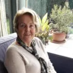 Femme souriante dans un salon avec plantes.