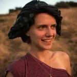 Femme souriante avec foulard en extérieur.