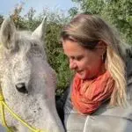 Femme souriante avec un cheval blanc.